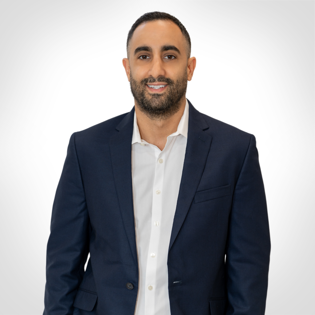 Smiling man in a navy blazer and white shirt against a white background