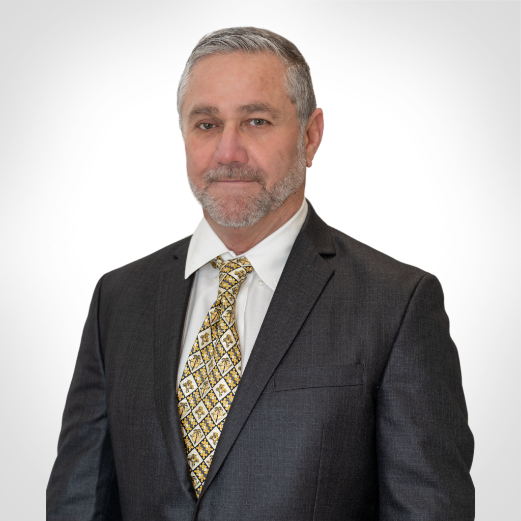 Portrait of a man in a dark suit and patterned tie against a light background