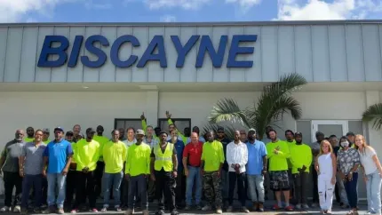 Group of people standing outside a building with a large “BISCAYNE” sign, many wearing bright yellow shirts.