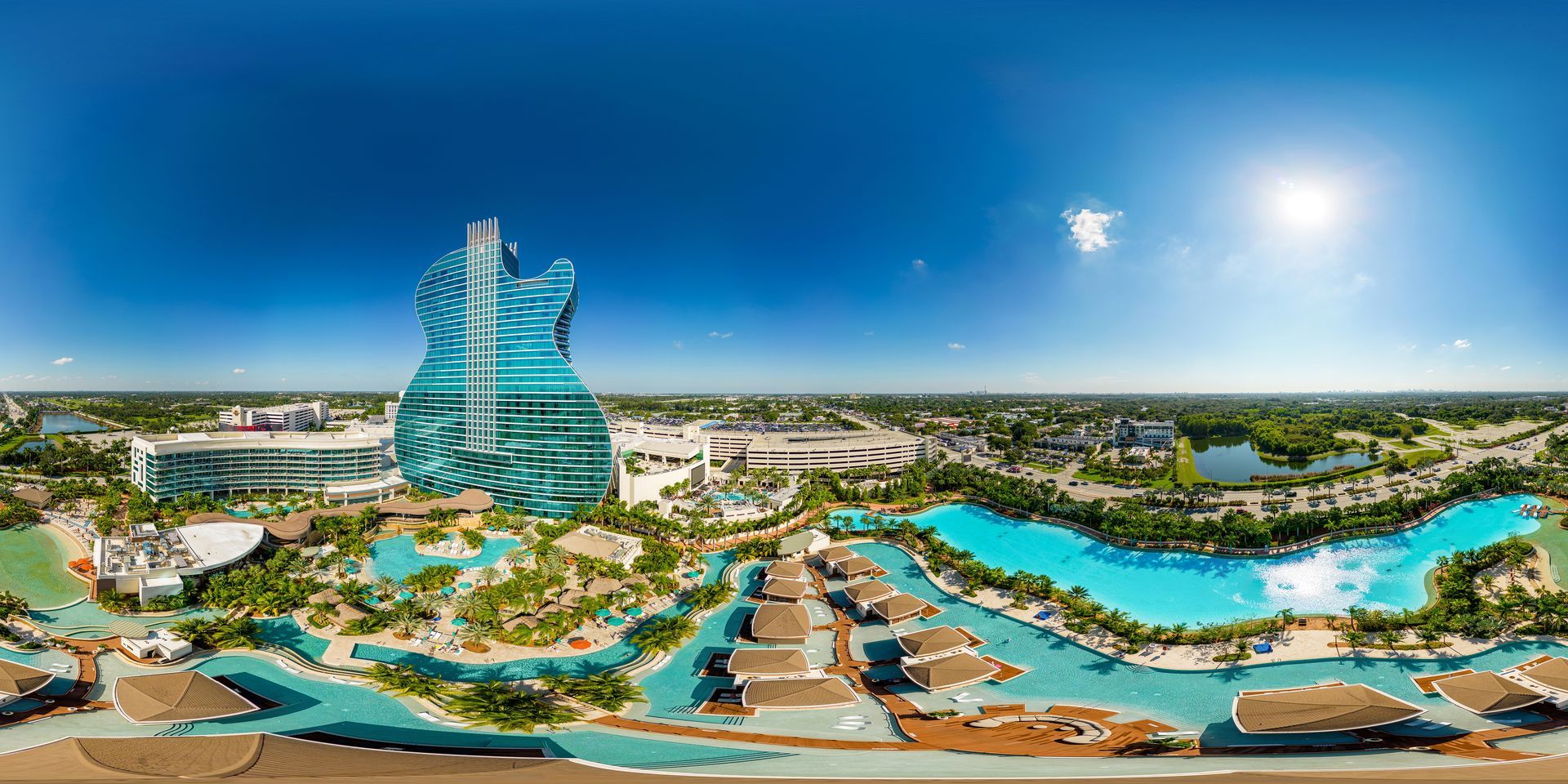 Futuristic seaside resort with turquoise lagoons, canals, and a tall glass tower under a blue sky