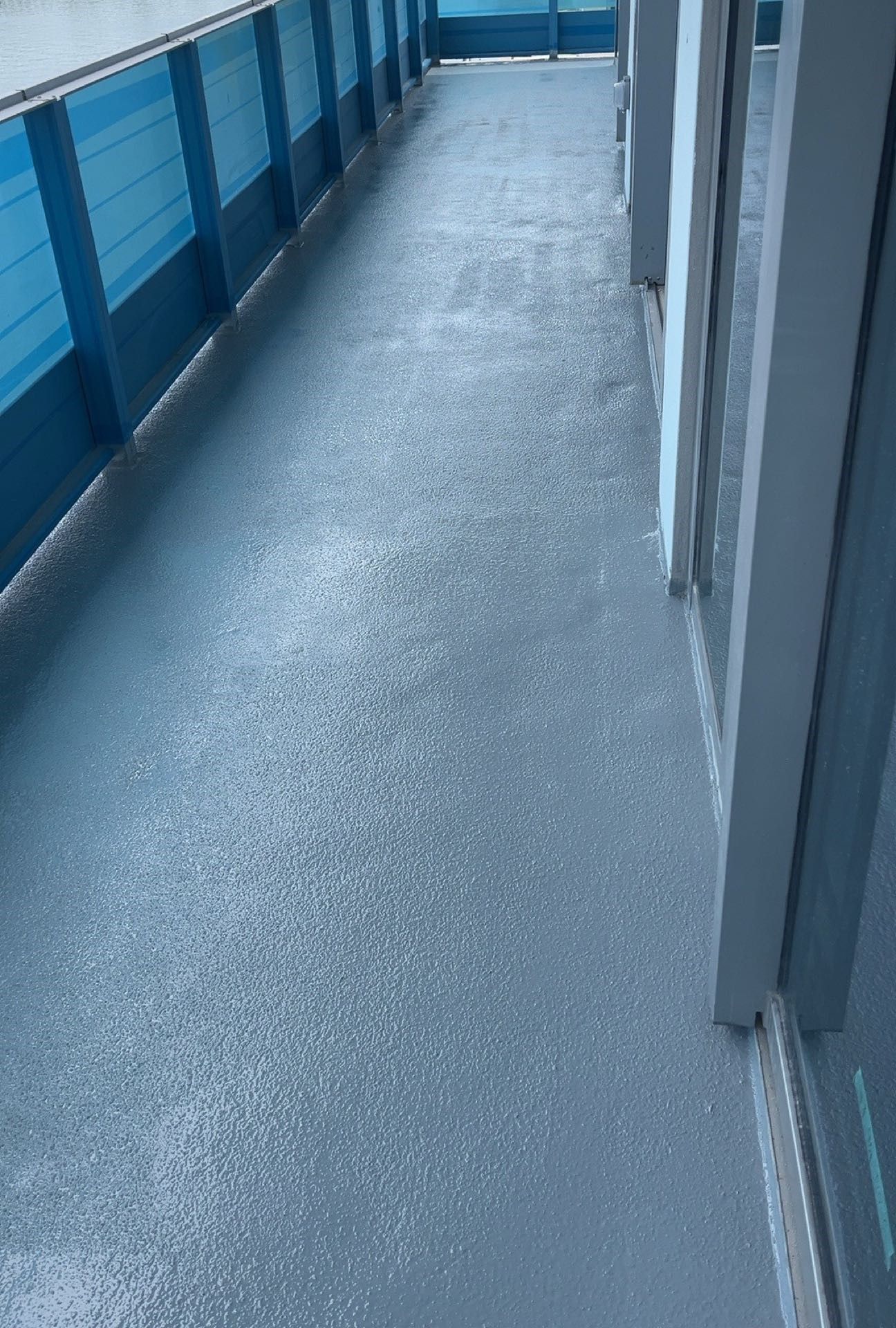 Empty blue-painted corridor with wet floor and railing along the left side