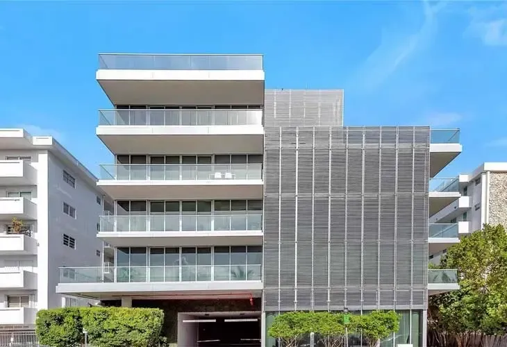 Modern multi-story office building with balconies and glass facade under a blue sky
