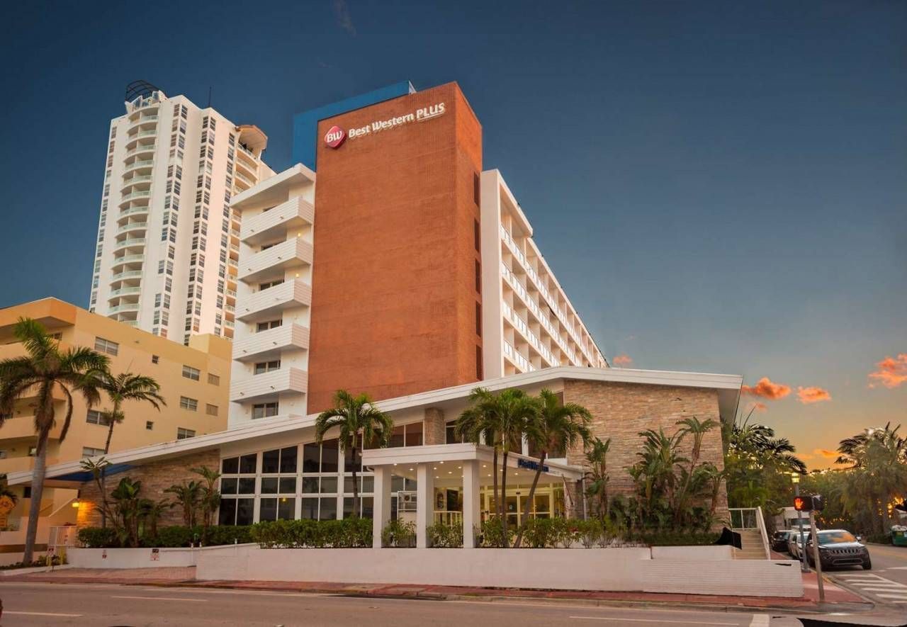 Modern hotel building with white and orange facade at sunset, seen from street level