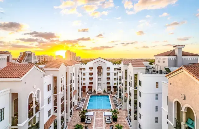 Sunset over a white resort courtyard with a central pool and palm-lined walkways