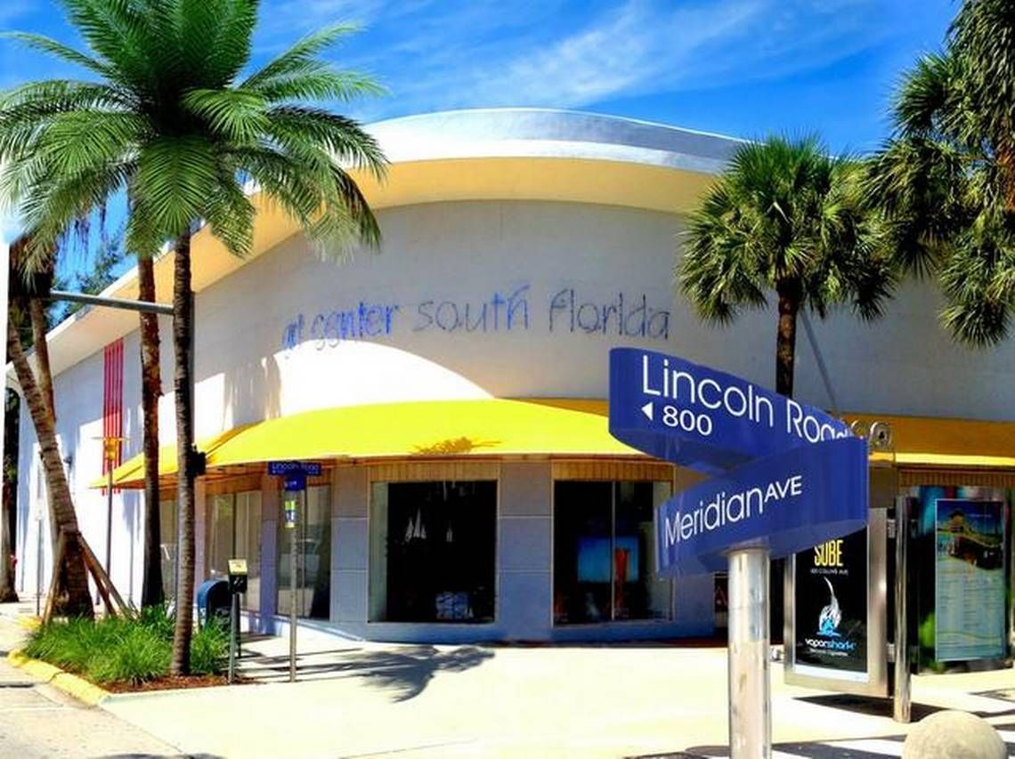 Art South Florida gallery with palm trees and Lincoln Road sign outside a yellow-and-white building