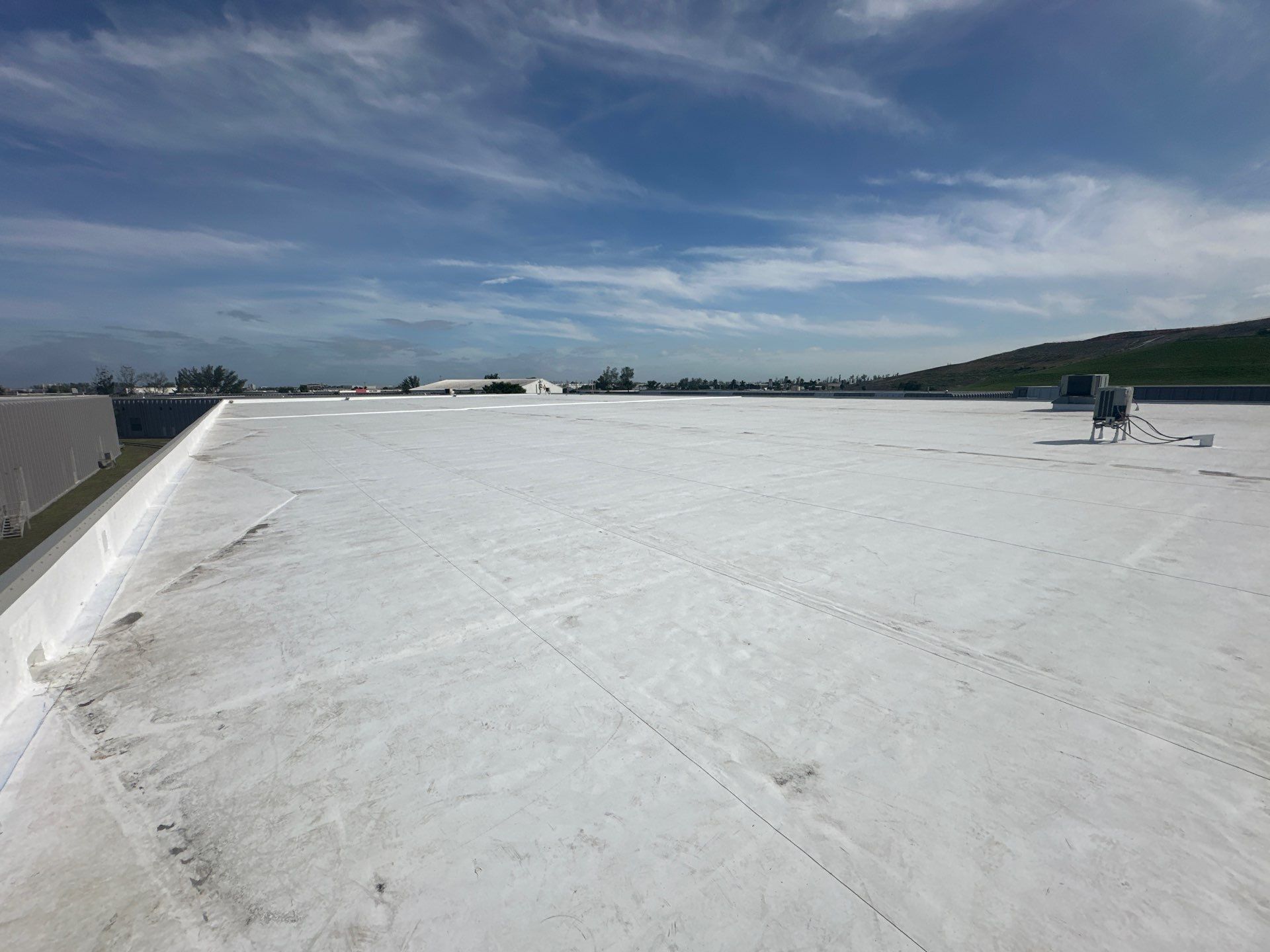 White rooftop under a bright blue sky with a few people near the right edge.