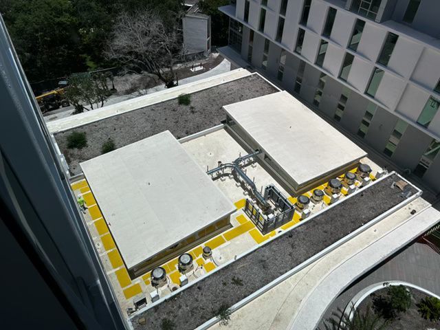Rooftop terrace with white structures, yellow seating, and a central metal sculpture in a courtyard.