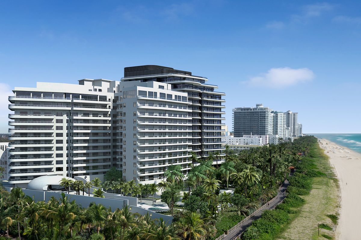 Modern beachfront high-rise condos beside a sandy beach and blue ocean under a clear sky