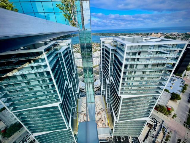 Aerial view of modern glass office towers with a city street and ocean in the background
