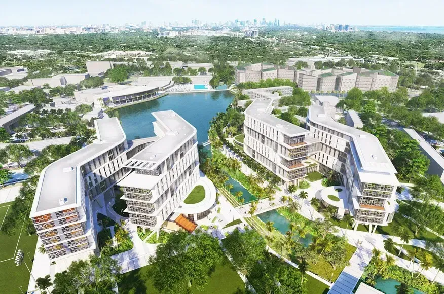Aerial view of modern glass office towers beside a waterfront under a blue sky
