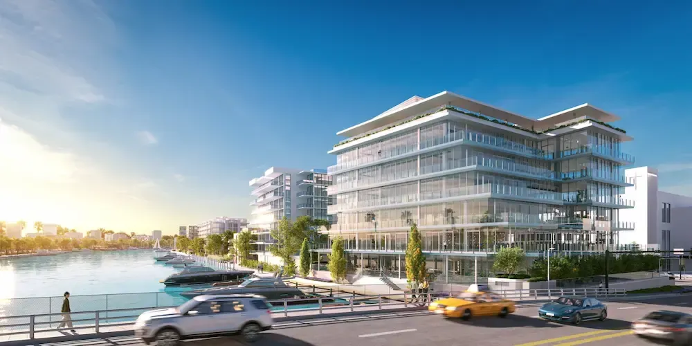 Modern waterfront office buildings with cars and pedestrians under a bright blue sky