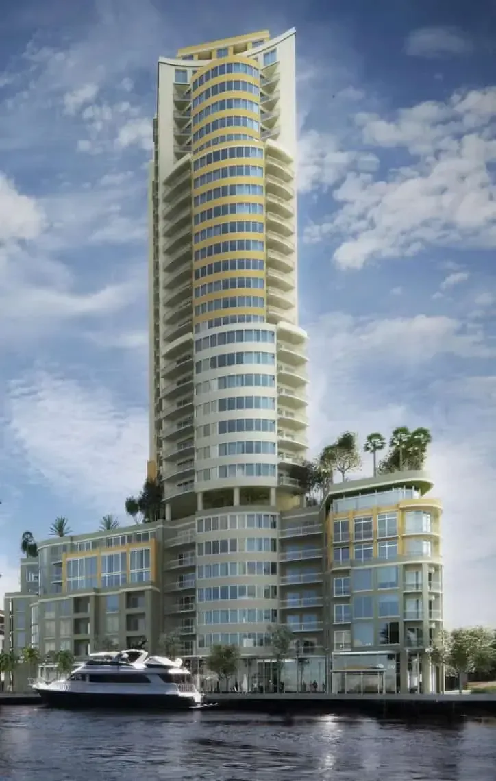 Modern waterfront high-rise with balconies, marina boats, and palm trees under a blue sky