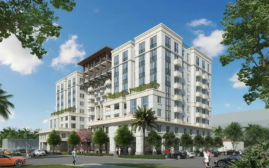 Modern white apartment building with balconies and trees under a blue sky