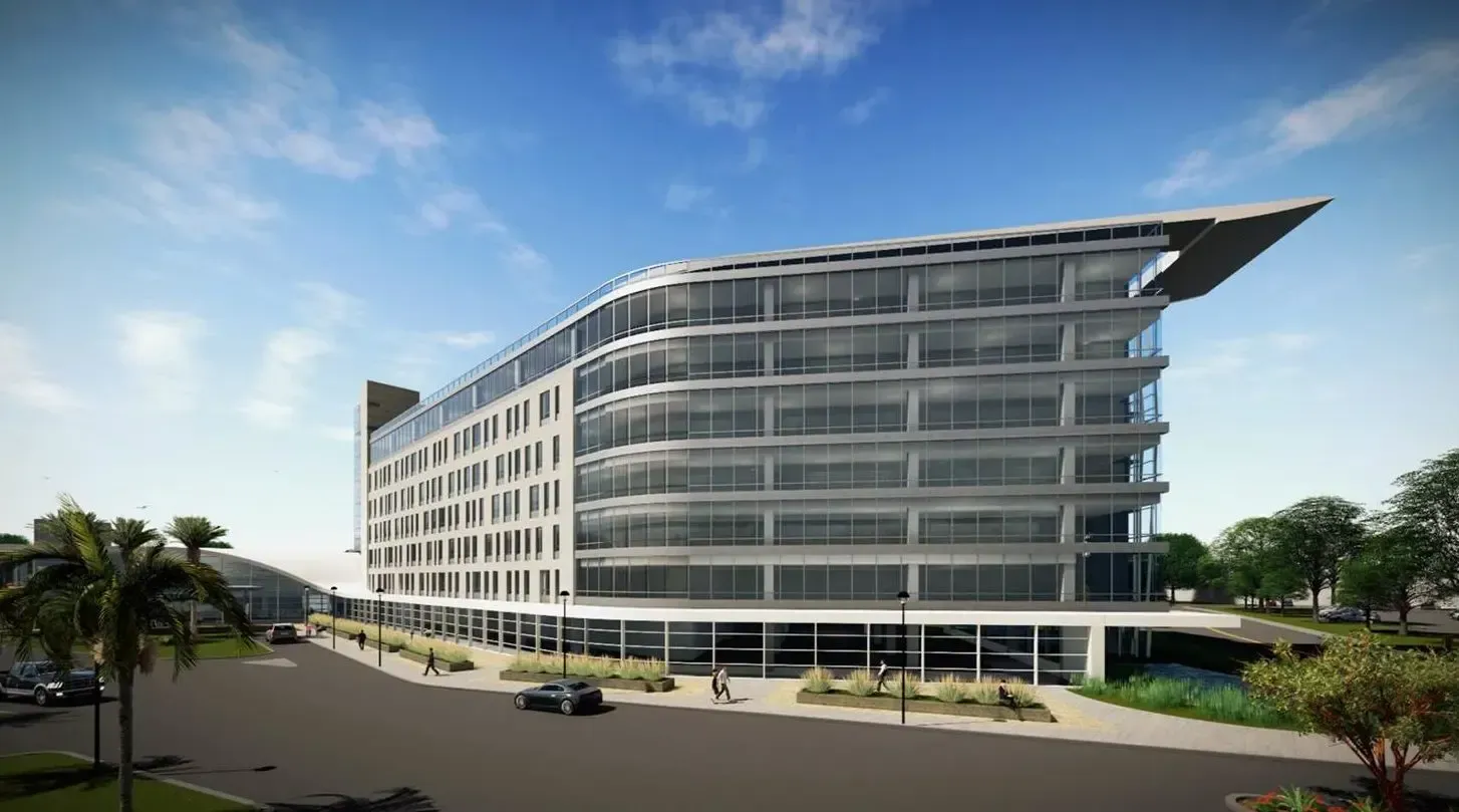 Modern glass office building with curved facade and rooftop overhang on a sunny street corner