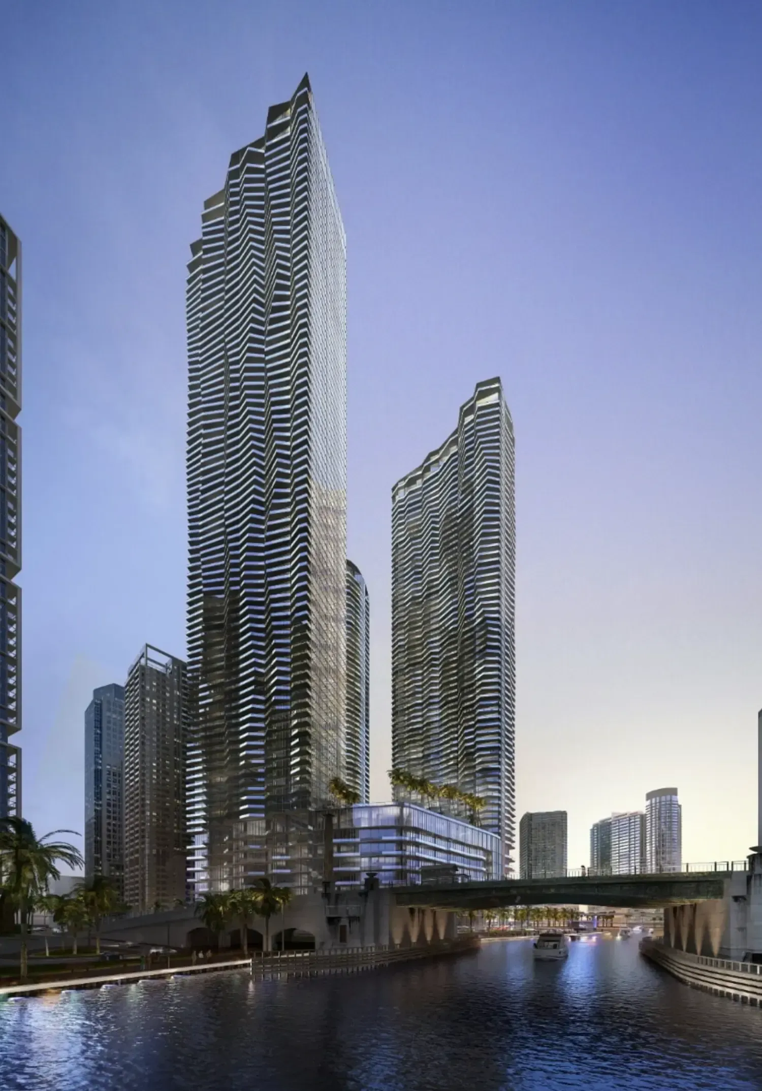 Two modern skyscrapers beside a canal at dusk, with reflections and a blue sky.