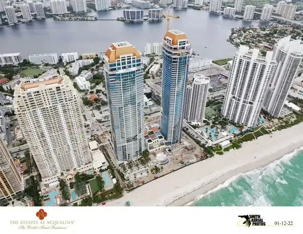 Aerial view of beachfront high-rise condos beside a river and ocean shoreline