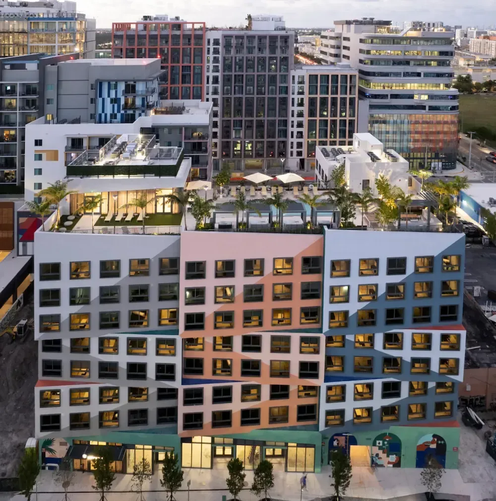 Modern apartment building with rooftop terraces in a dense urban neighborhood at dusk