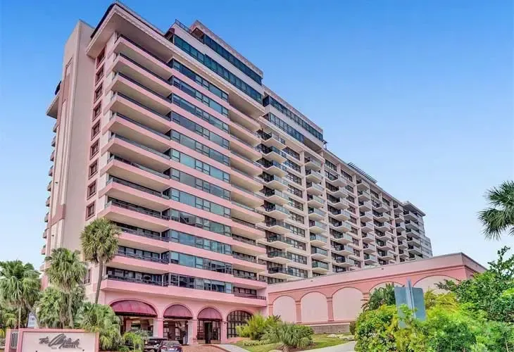 Pink high-rise apartment building with balconies under a clear blue sky