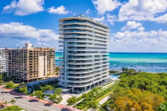 Modern beachfront high-rise condo tower beside the ocean under a blue sky