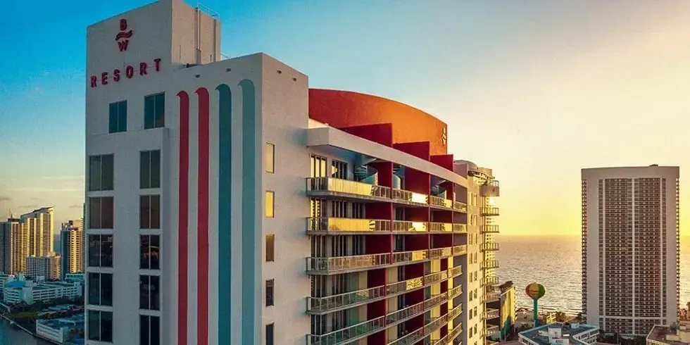 Sunset view of a resort hotel with balconies and ocean in the background