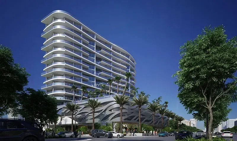 Modern white high-rise apartment building with balconies, palm trees, and cars under a clear blue sky