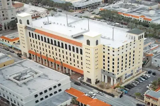 Aerial view of a large beige and white hospital building in a dense urban area.