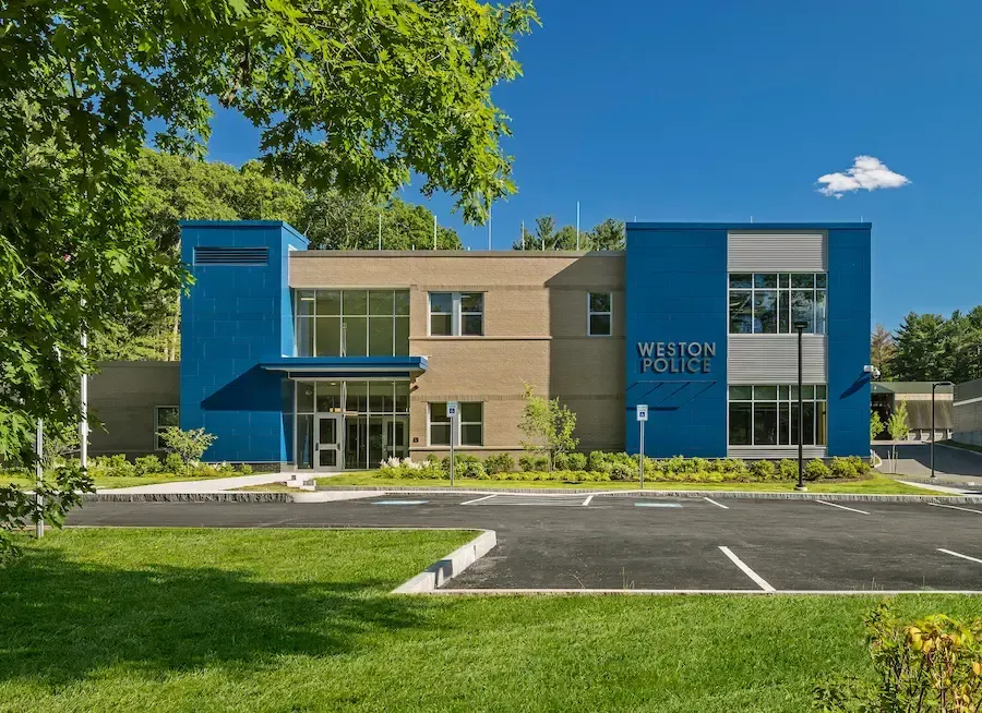 Modern two-story building with blue accents, glass entry, and empty parking lot in front