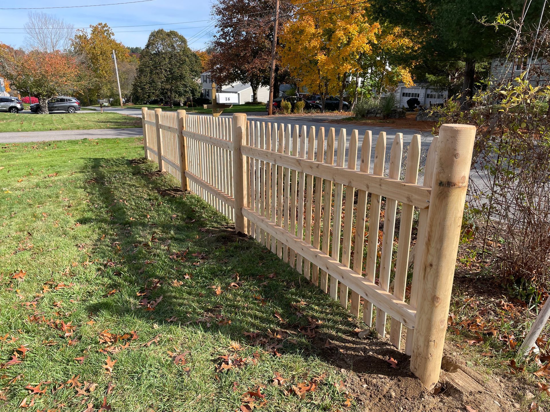 A wooden picket fence is sitting in the middle of a grassy field.