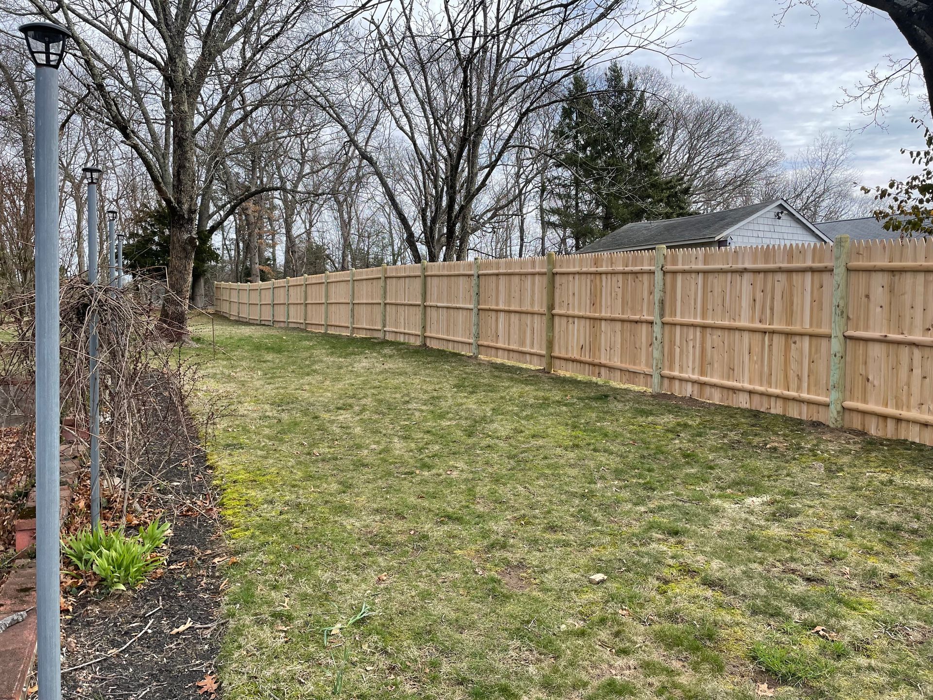 A wooden fence surrounds a lush green yard.