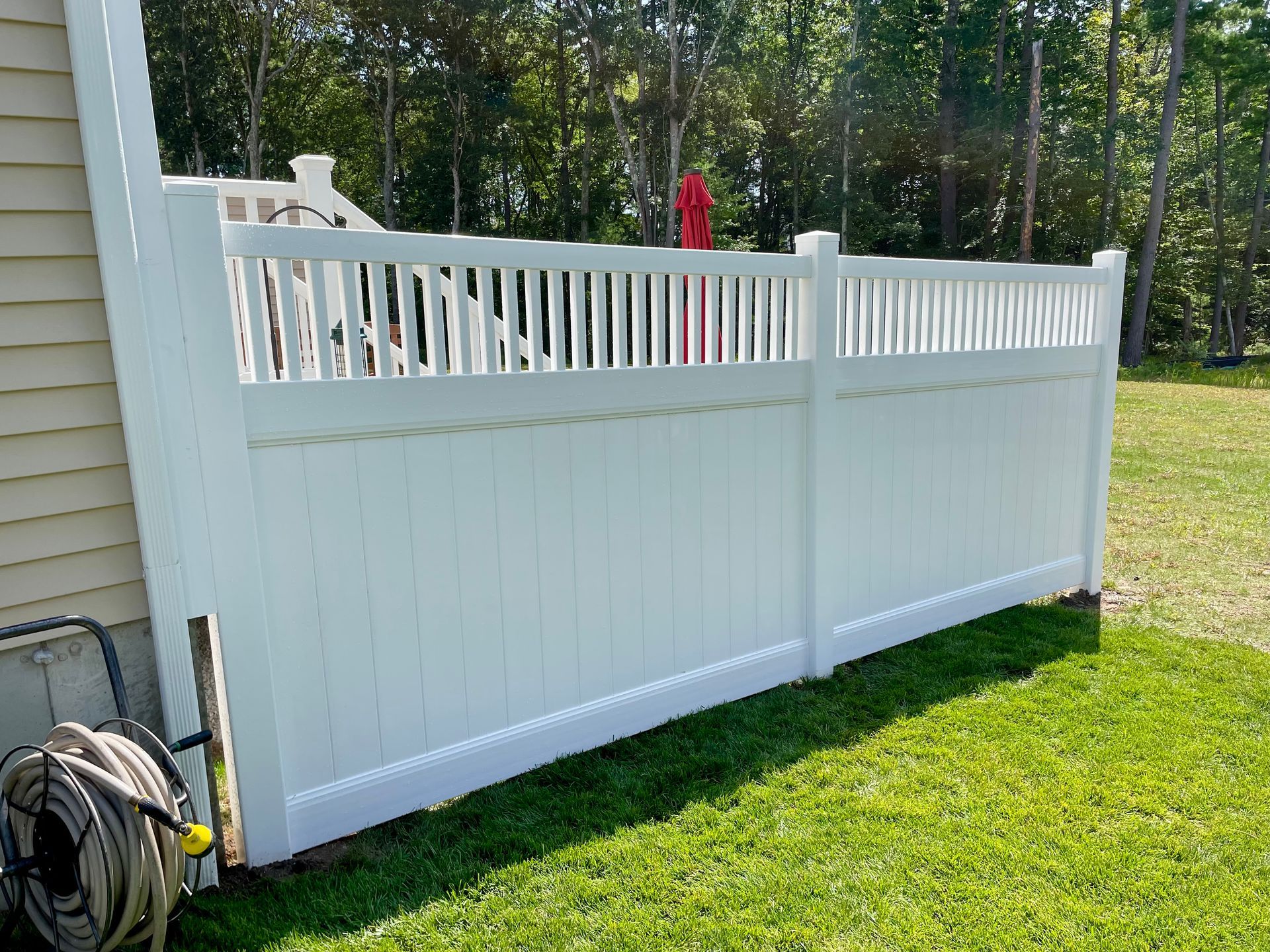 A white fence is sitting in the grass next to a house.