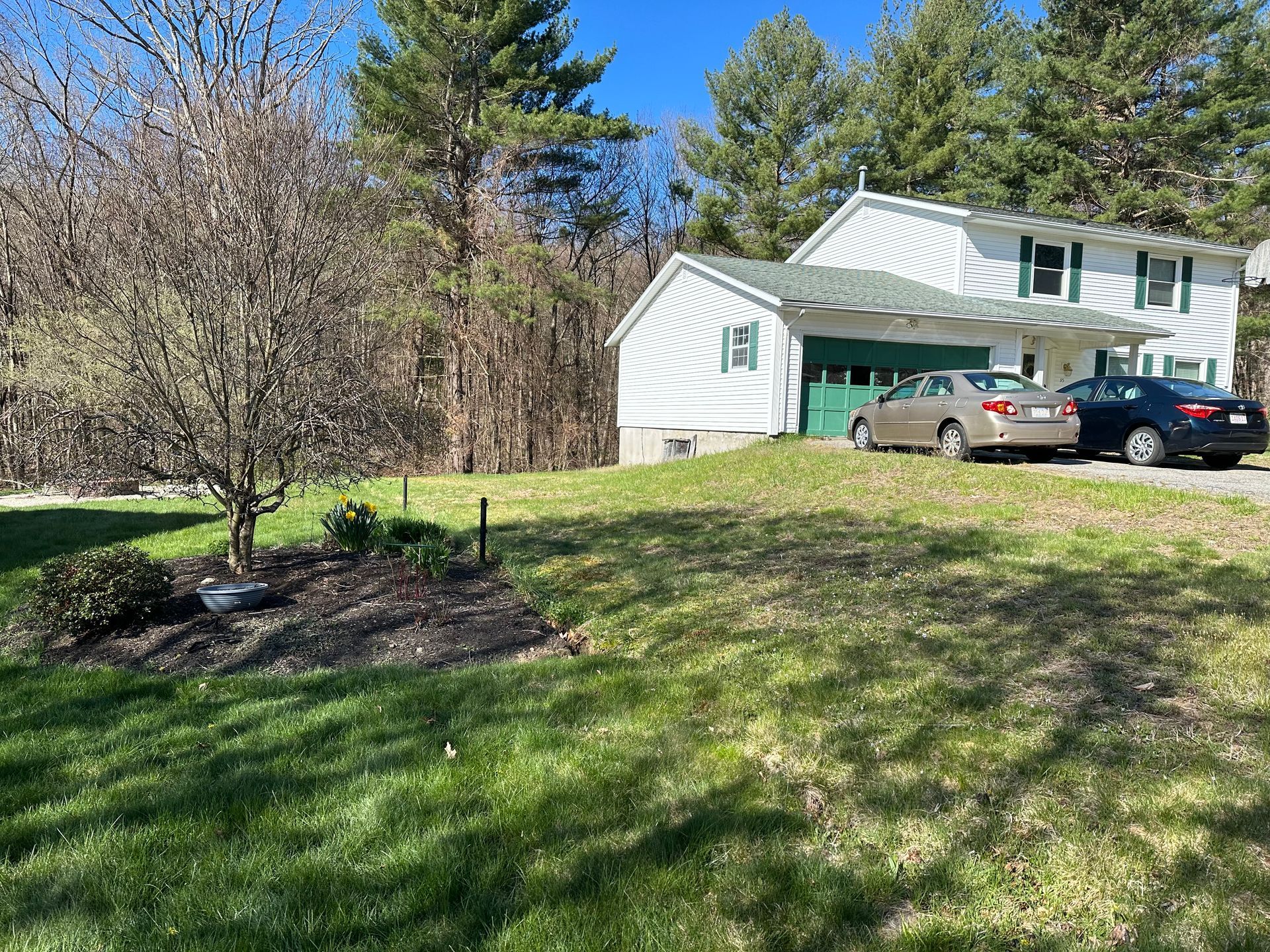 A white house with two cars parked in front of it.