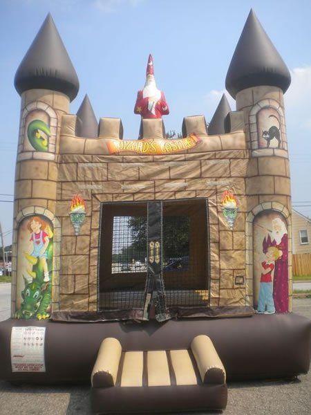 A wizard-themed inflatable bounce house with stone-textured walls, castle turrets, and an entrance step.