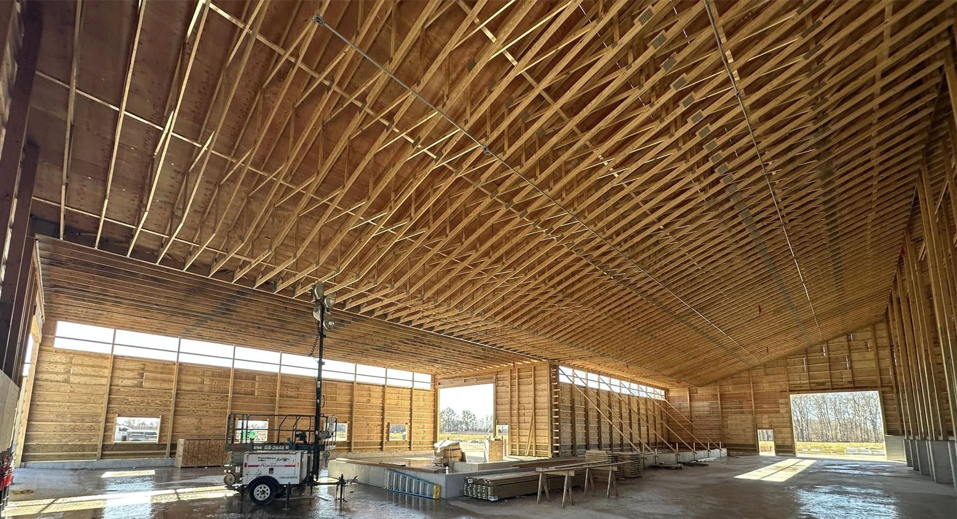 Interior of a large wooden building under construction; trusses and framing visible.