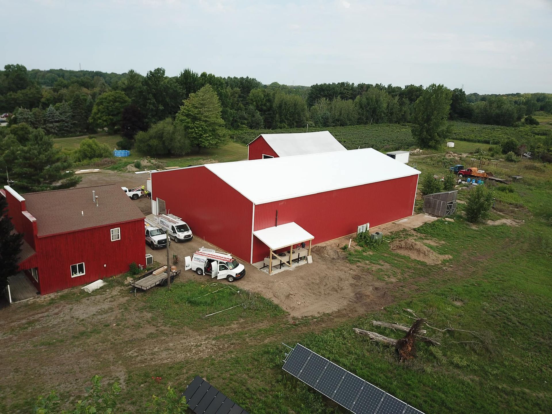 Red barns and outbuildings on a rural property, with white trucks parked outside the main barn.