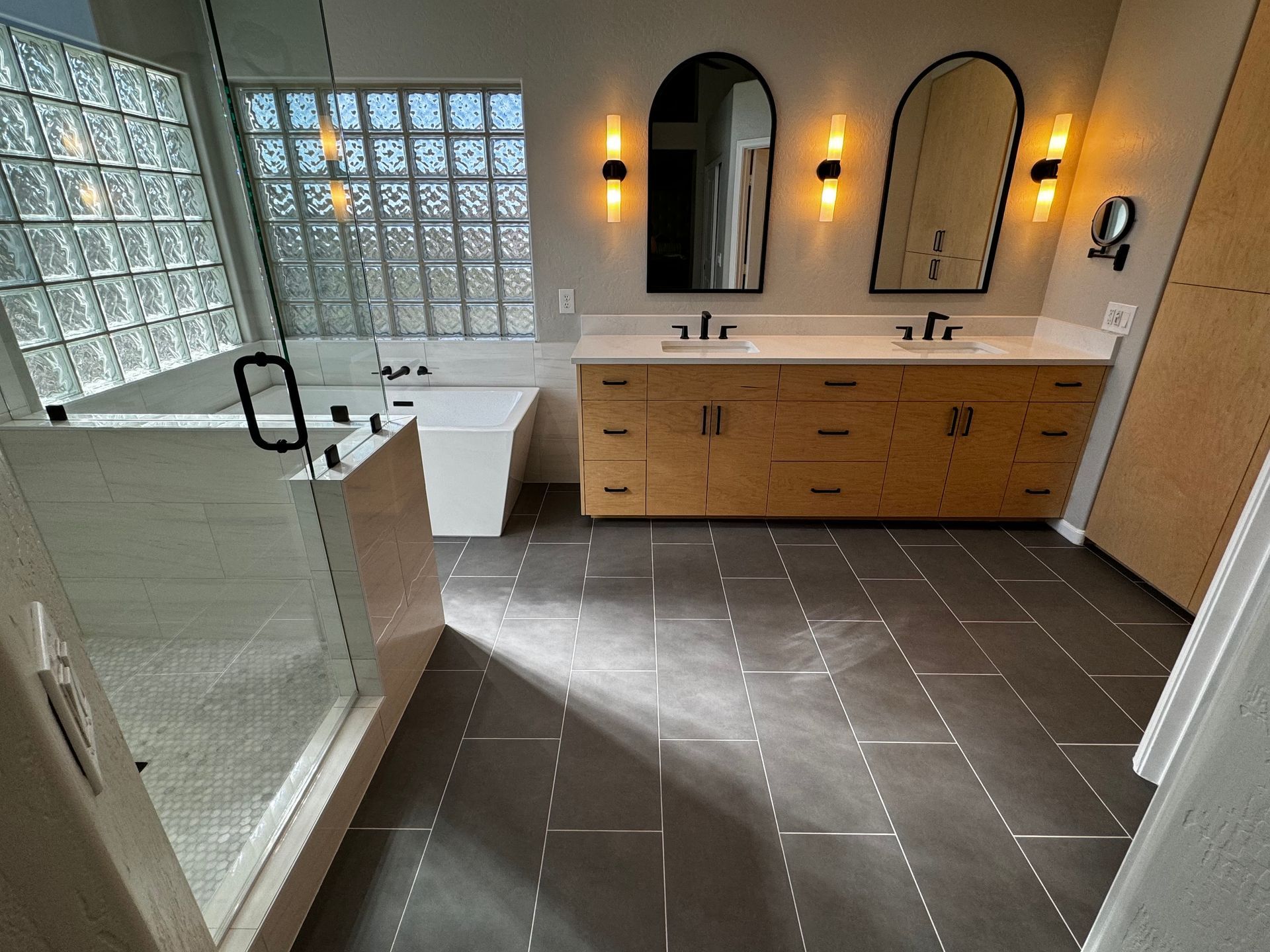 A bathroom with two sinks , a tub , and a walk in shower.