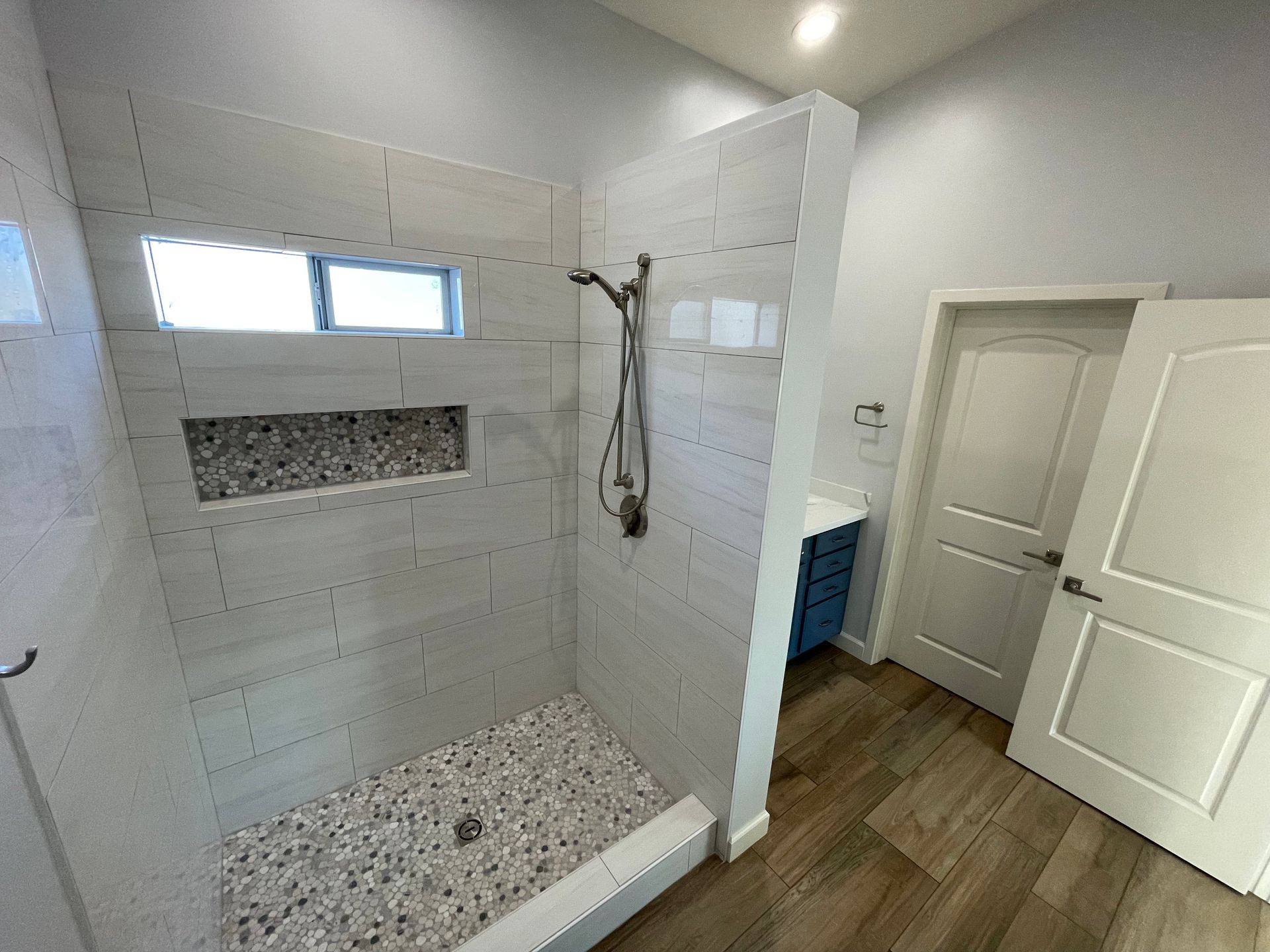 A bathroom with a walk in shower and a window.