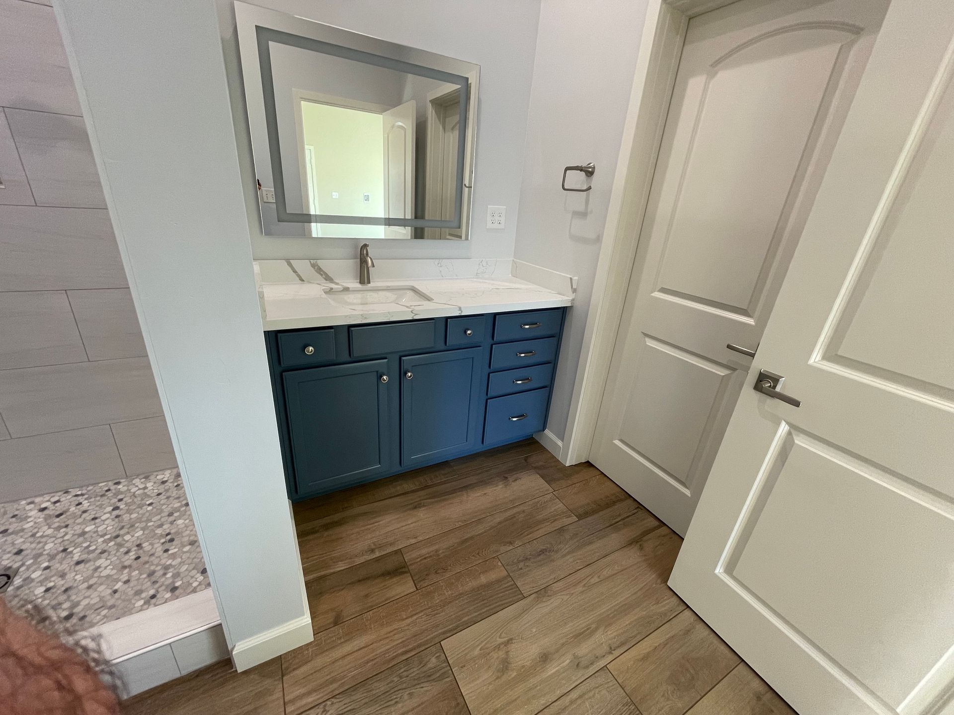 A bathroom with a sink , mirror , and walk in shower.