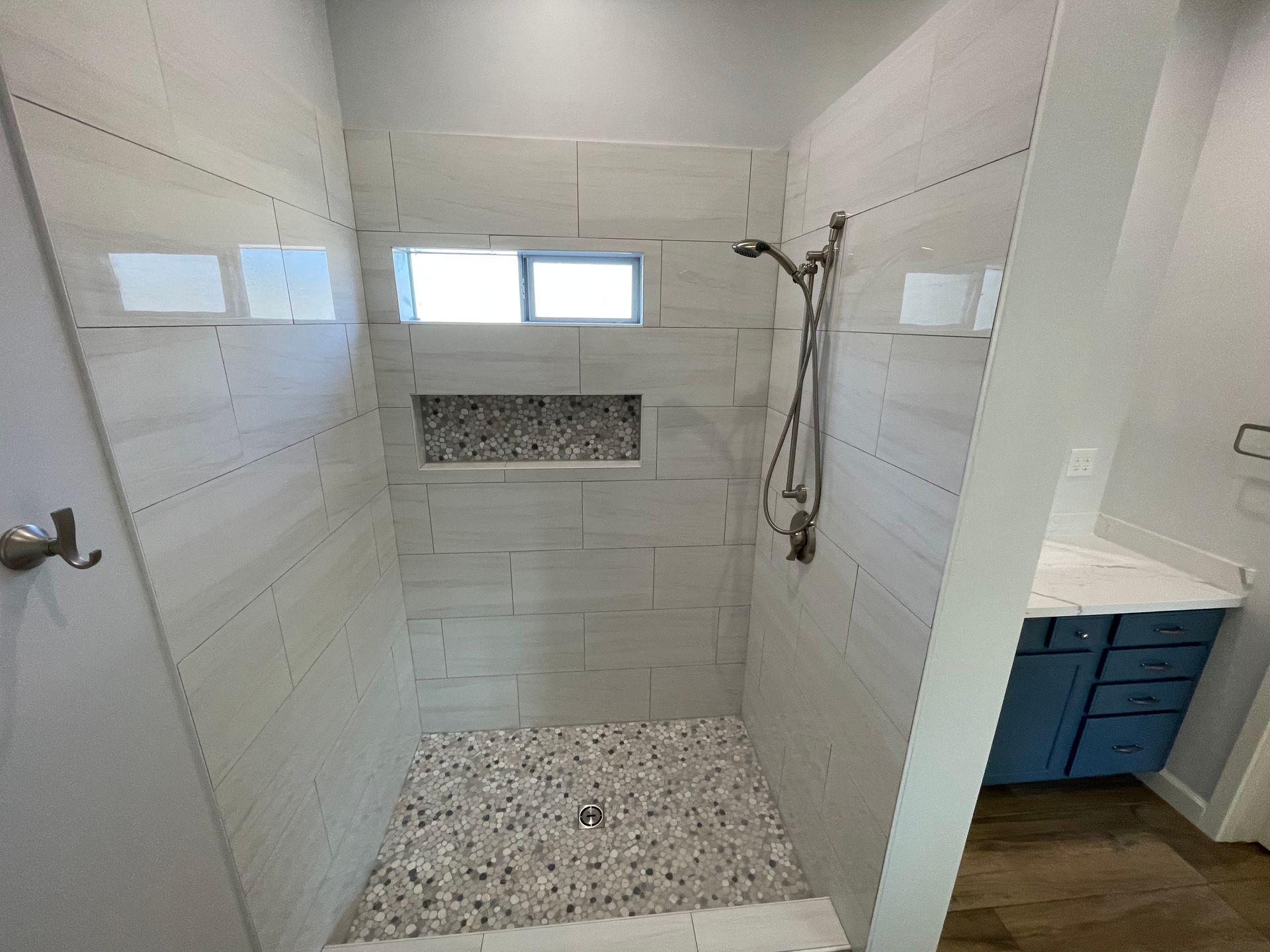 A bathroom with a walk in shower and a window.