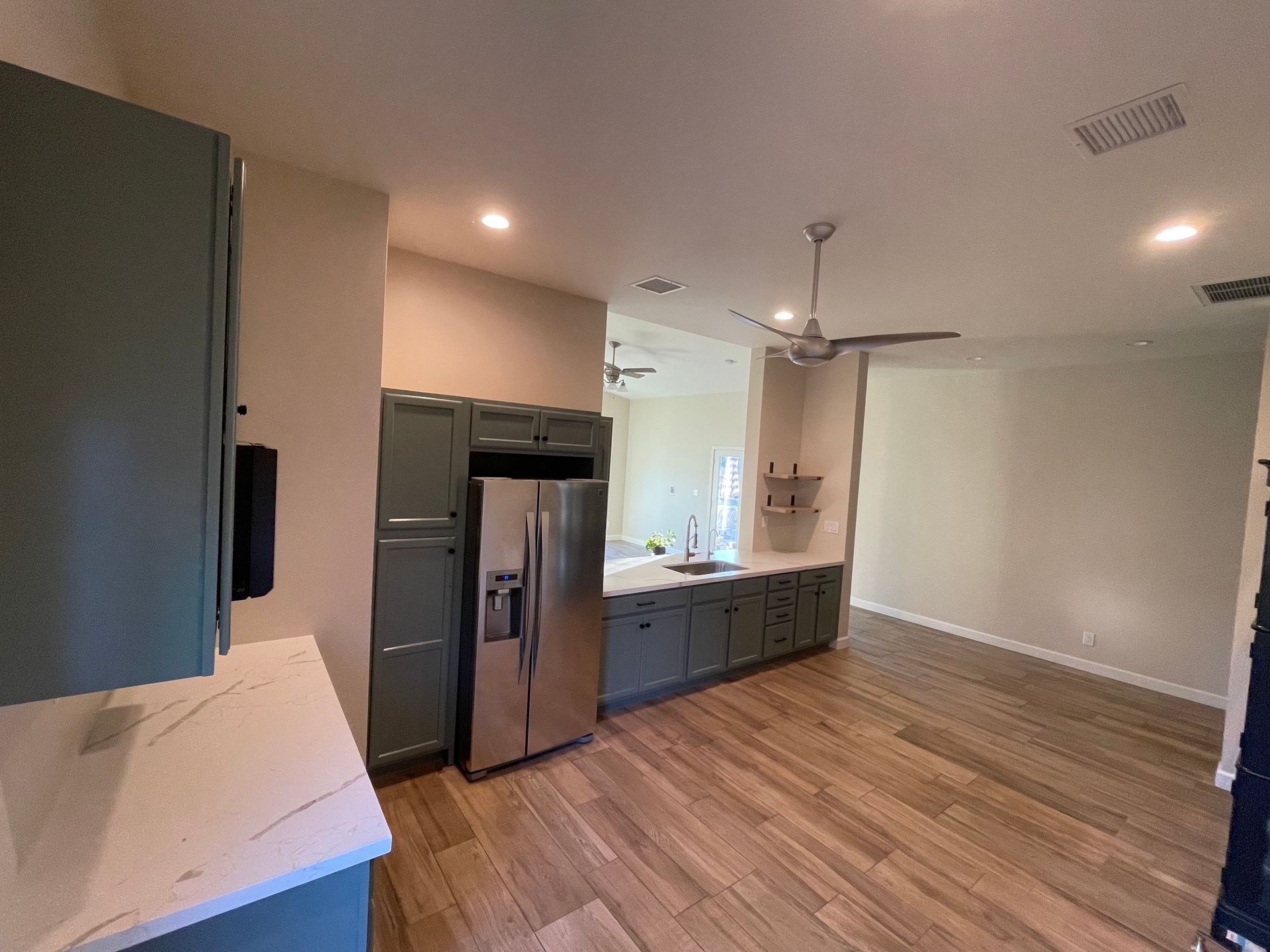 A kitchen with a refrigerator , sink , and ceiling fan.