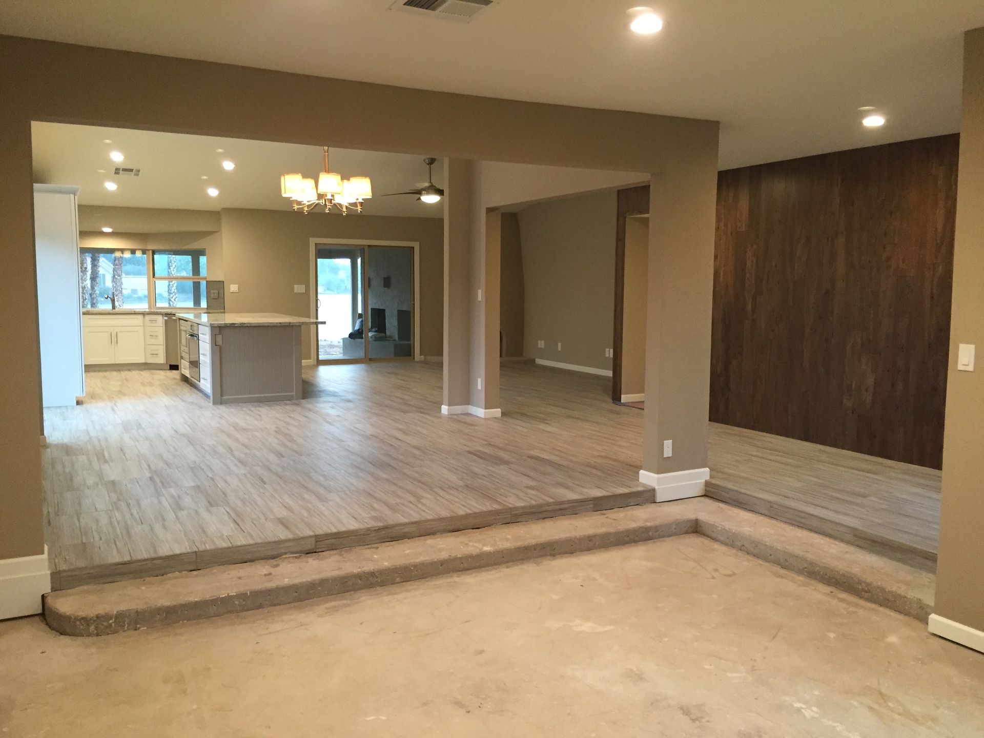 A large empty room with a wooden floor and a kitchen in the background.