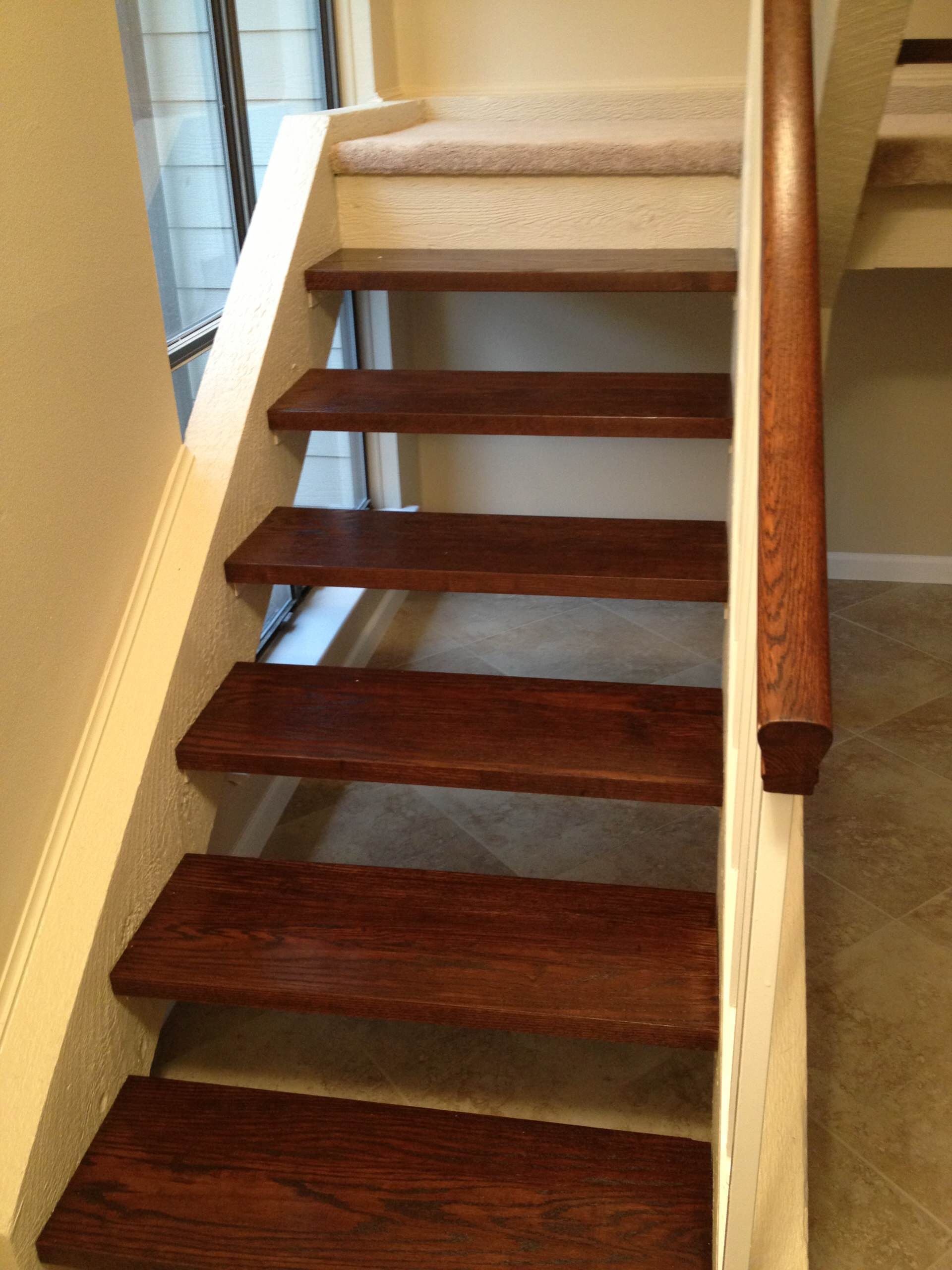 A wooden staircase with a white railing in a room