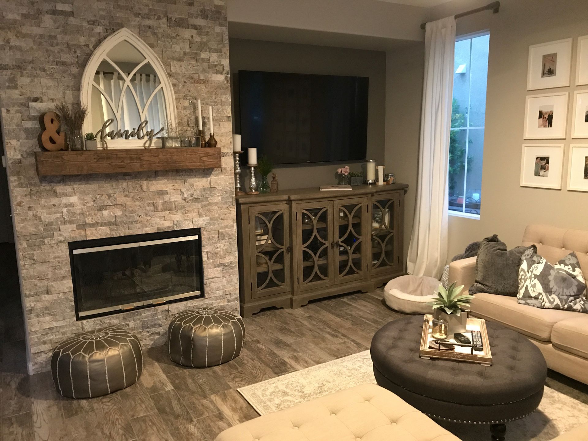 A living room with a fireplace , couch , ottoman and television.