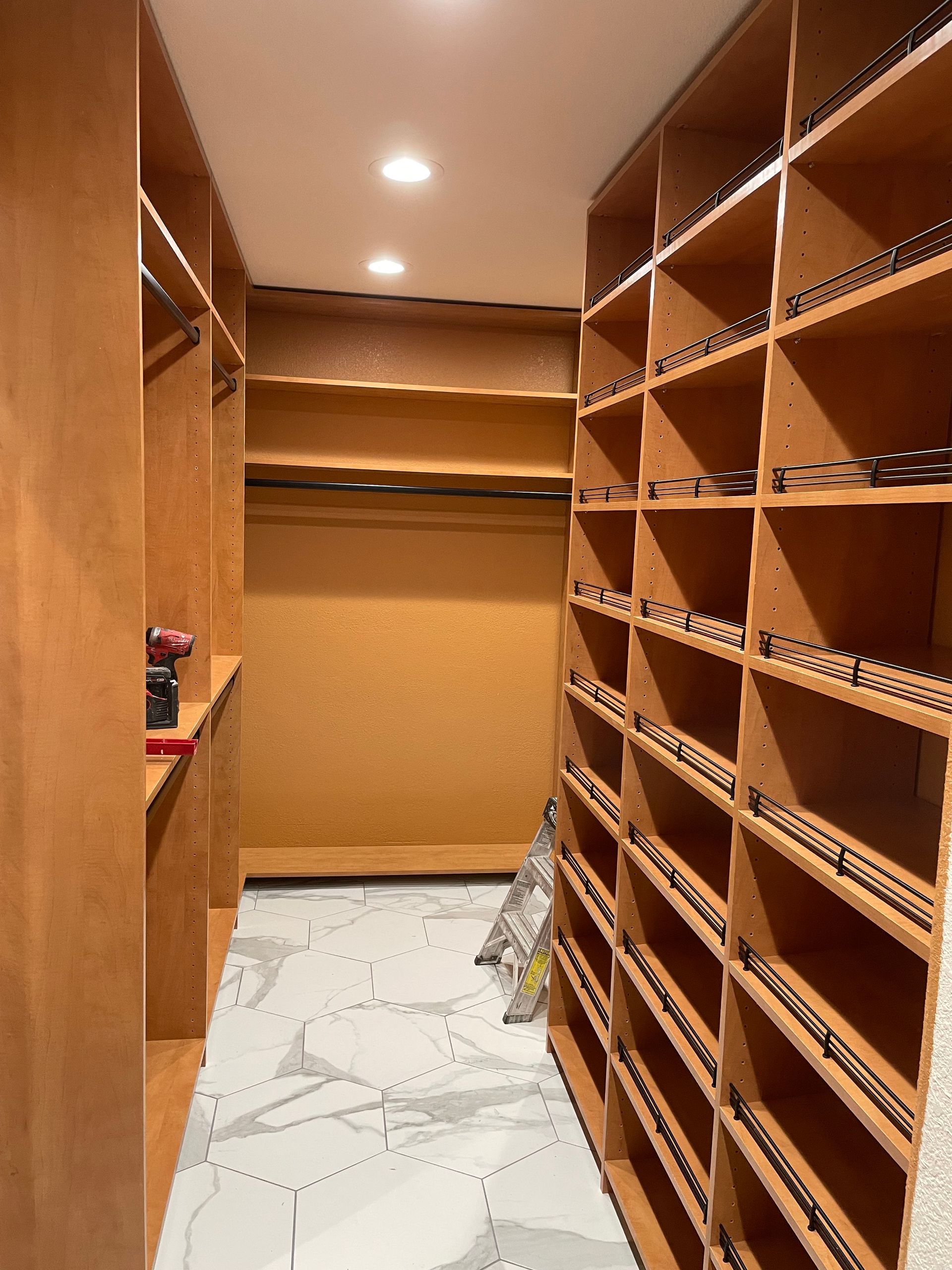 A walk in closet with lots of shelves and a marble floor.