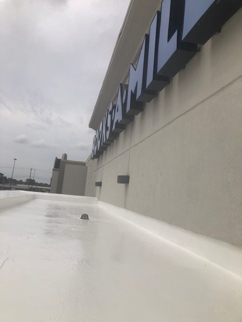 A white silicone coated building roof with a blue sign on it