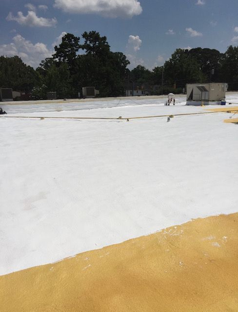 A large white silicone coated roof with trees in the background