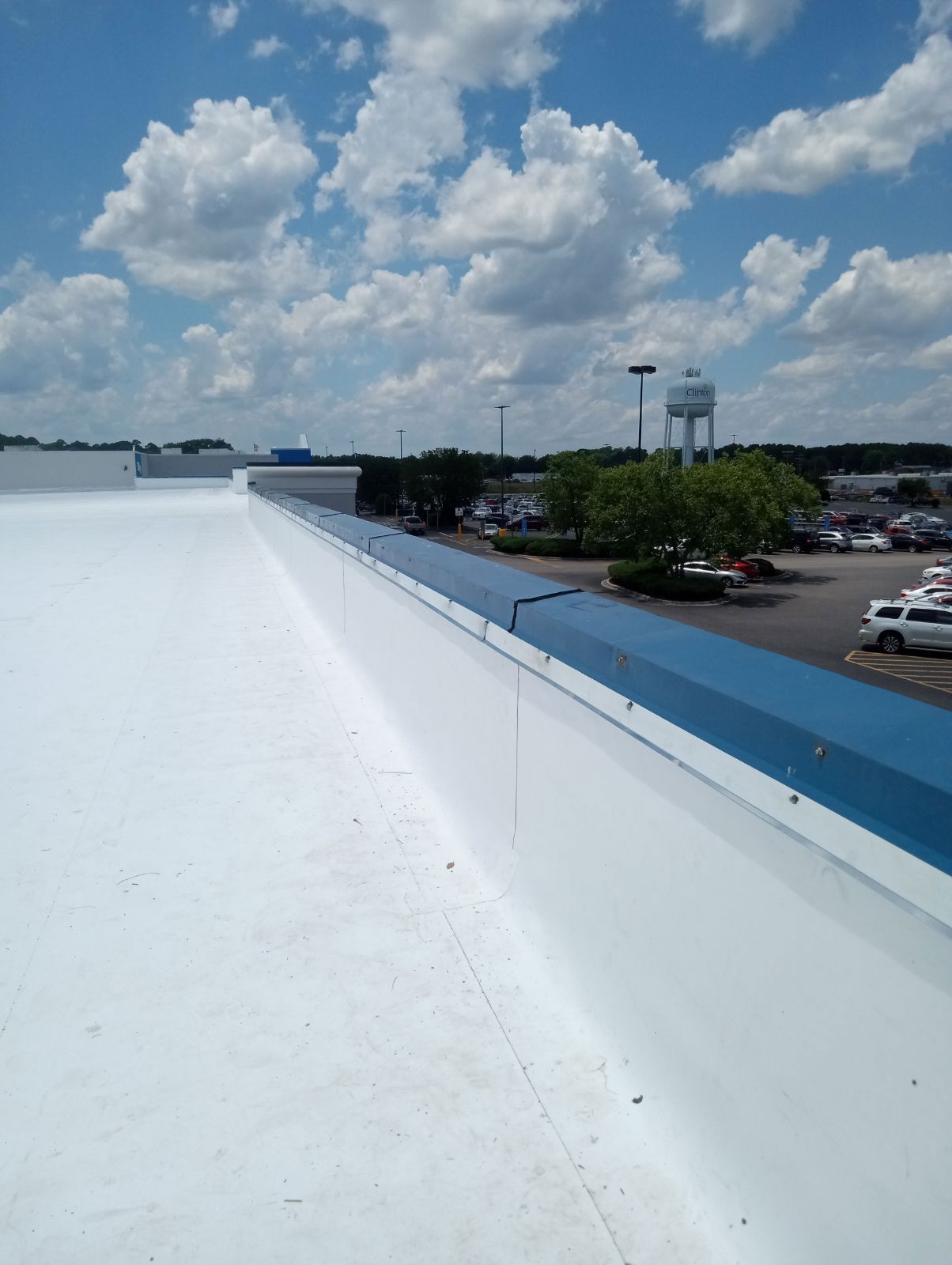 A white roof with a blue trim and a parking lot in the background