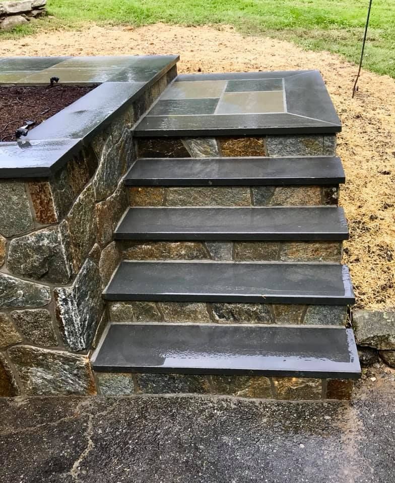Stone steps leading up from a patio, with a stone wall and planter box.
