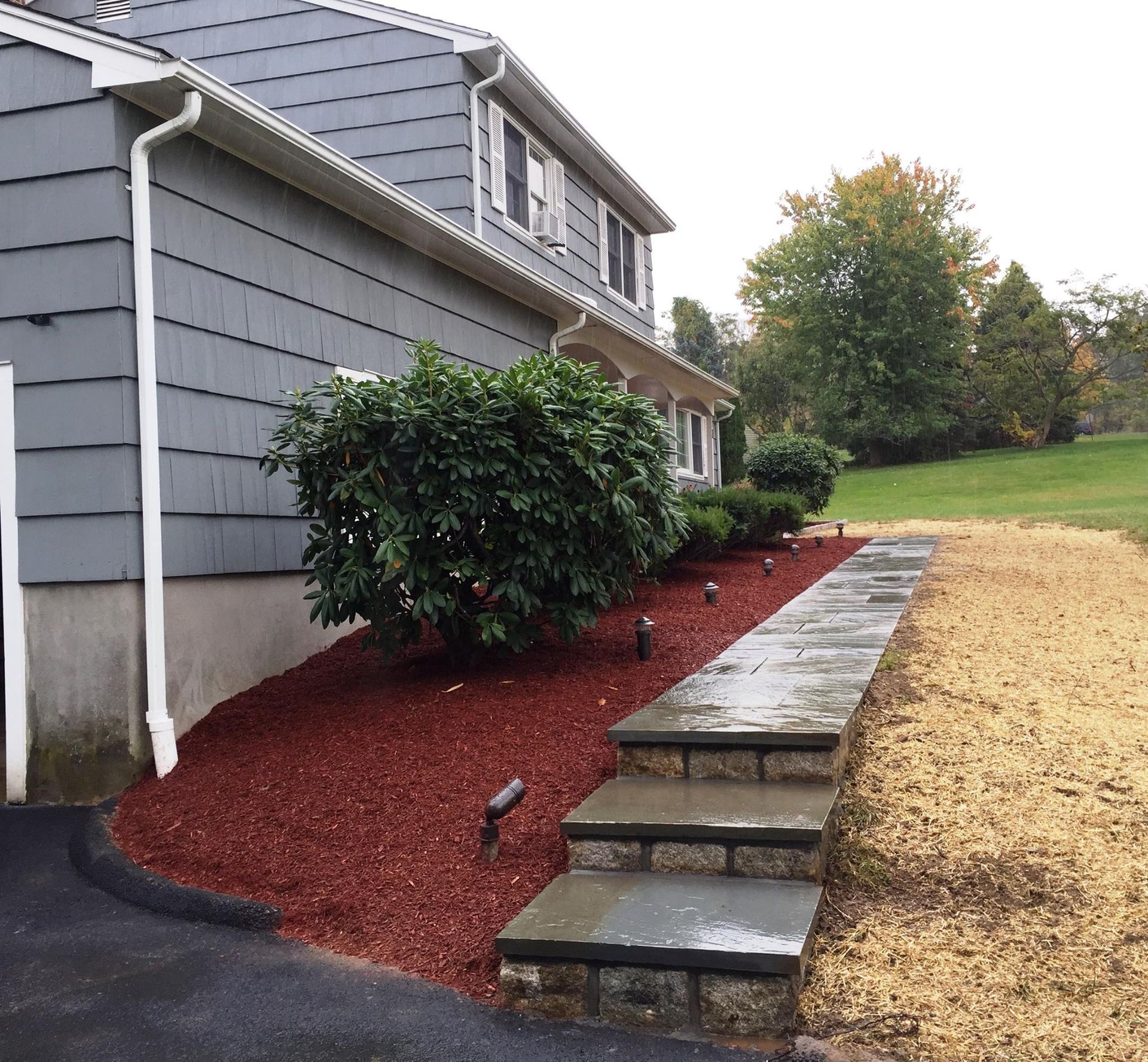 House exterior with mulched landscaping, stone steps, and path.