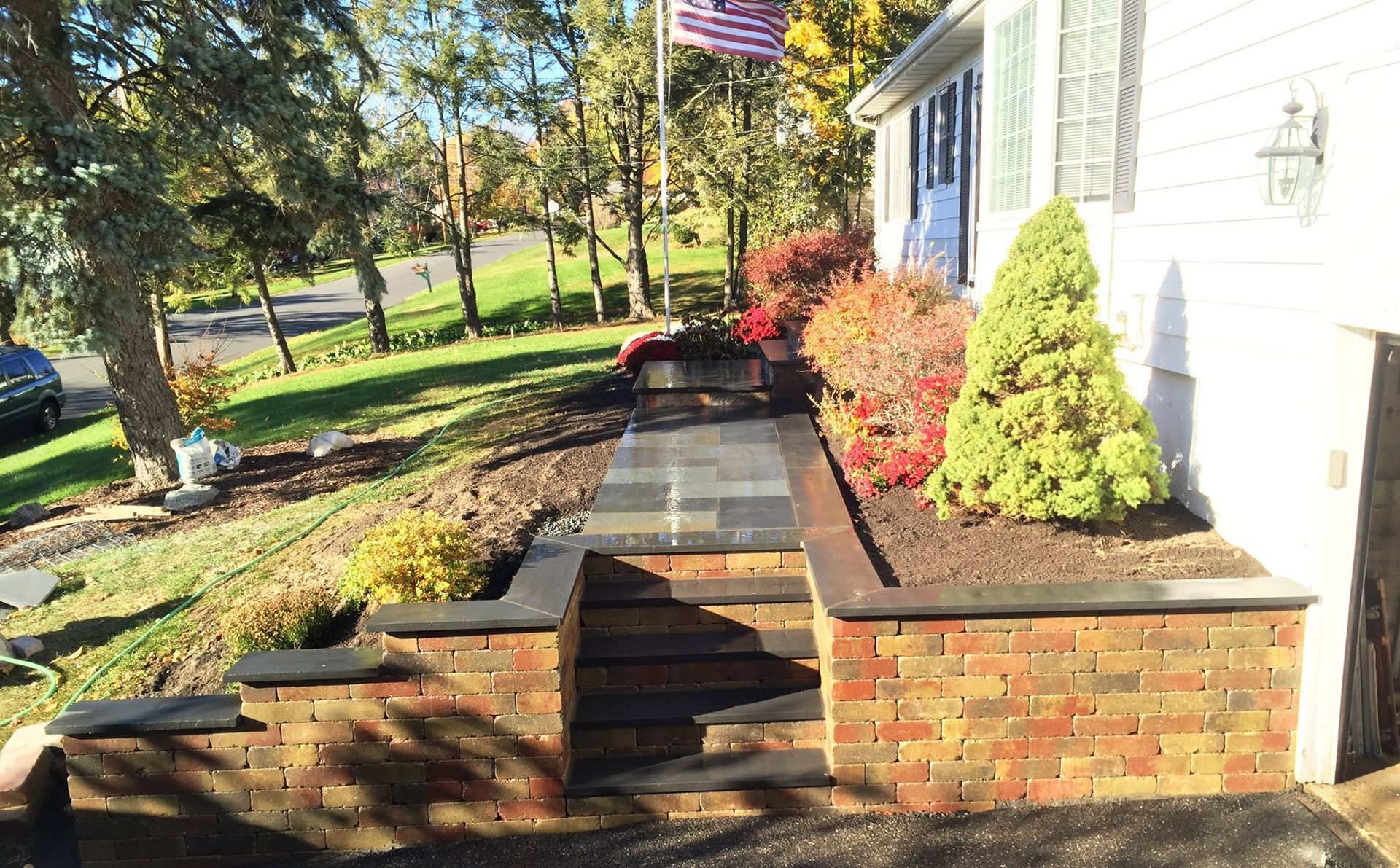 Brick steps leading up to a house with a garden bed filled with colorful plants.