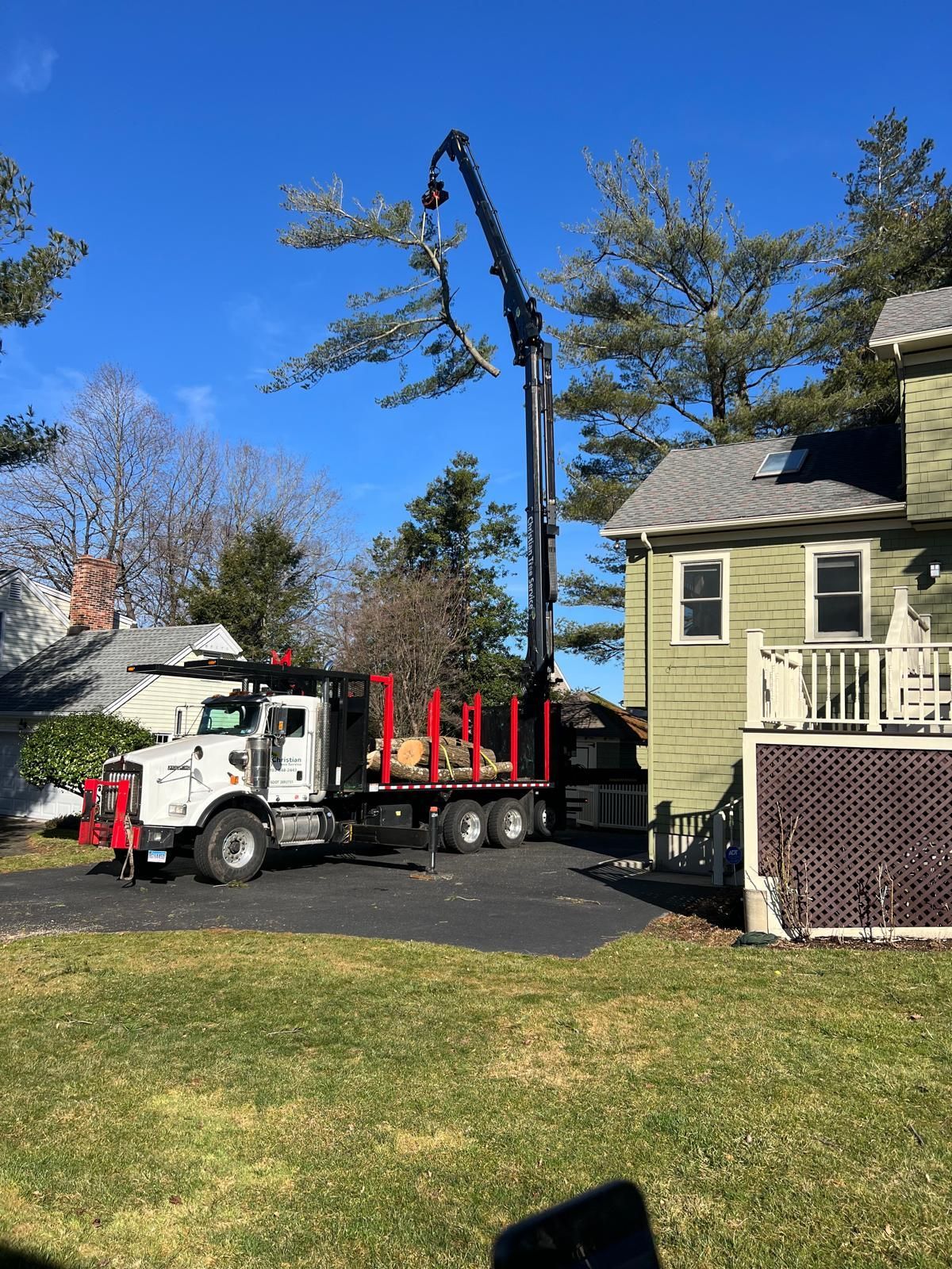 A truck with a crane attached to it is parked in front of a house